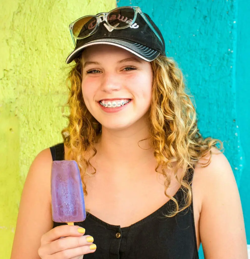 a woman with braces holding a popsicle