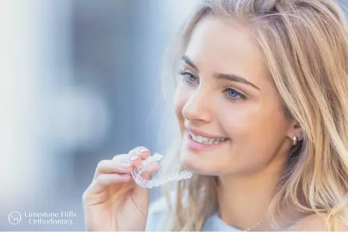 a woman holding a clear Invisalign vs Braces Cost