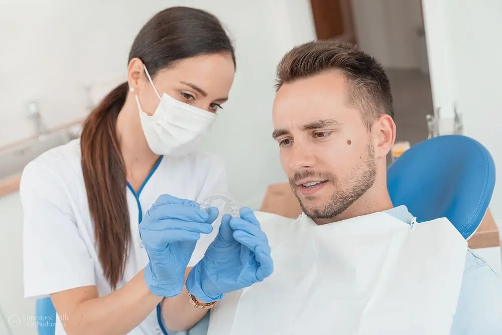 What does an orthodontist do? Orthodontist showing Invisalign clear aligners to patient during consultation