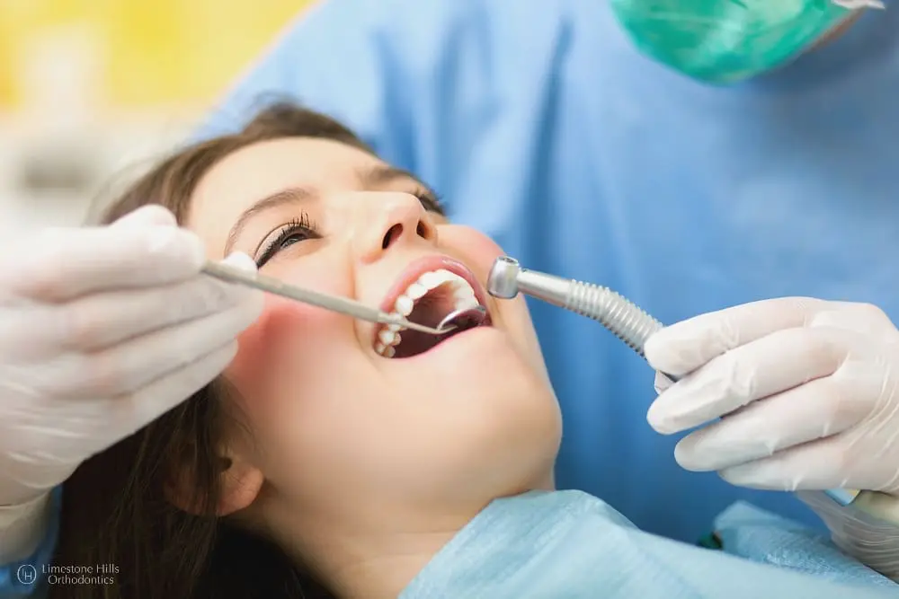 Orthodontist caring for a female patient during a dental procedure after  she knows how to speed up orthodontic treatment