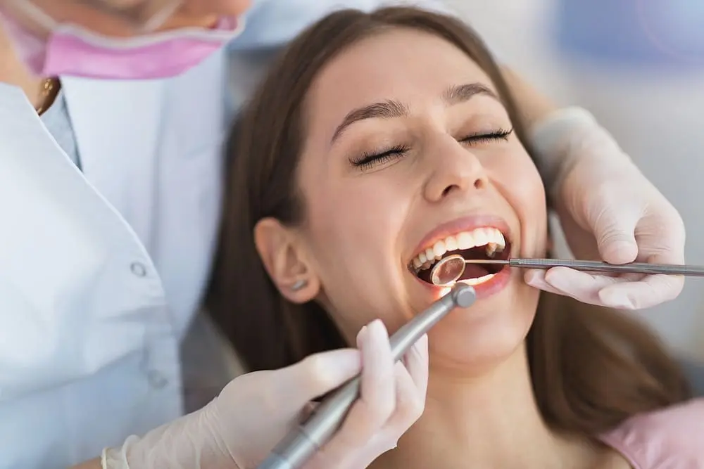 Orthodontist examining a female patient's teeth during a checkup. after wondering about "Do I Still Need to See a Dentist During Orthodontic Treatment?"