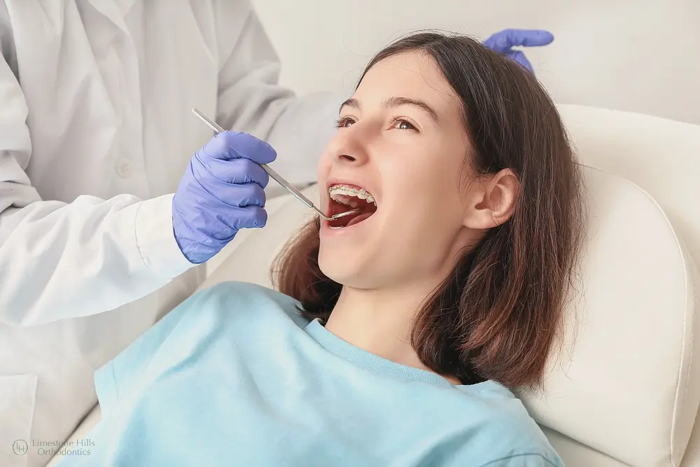 A dentist examines a teen with braces at Limestone Hills Orthodontics in Austin, TX, showcasing treatment options by age.