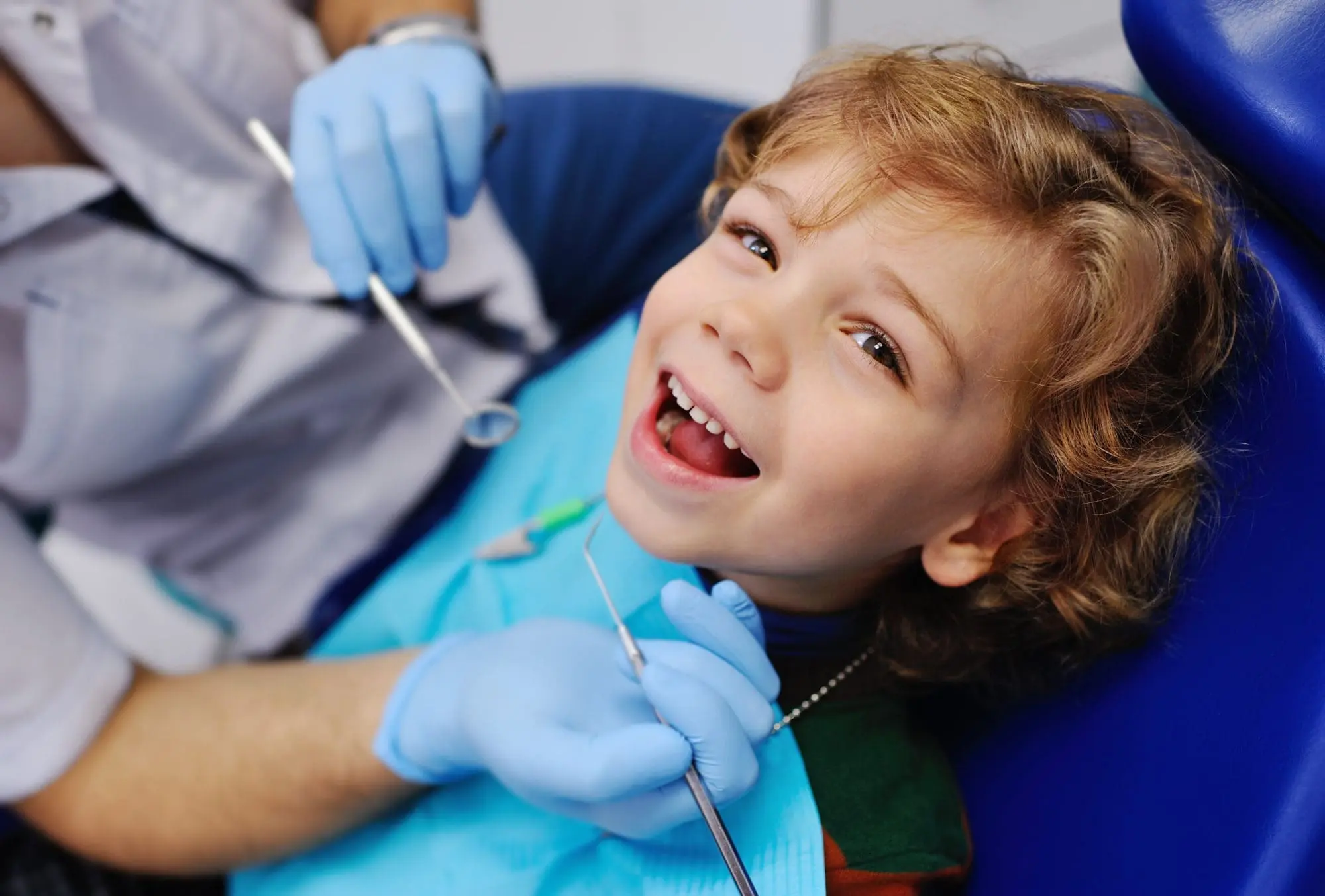 A young child, who appears to be of Caucasian descent based on their features and complexion, smiles during a dental examination. Limestone Hills Orthodontics in Austin, TX, offers pediatric orthodontic care.