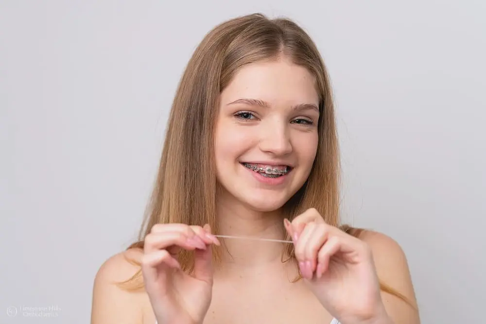 Smiling woman with traditional braces for treats underbite at Limestone Hills Orthodontics in Austin, TX.