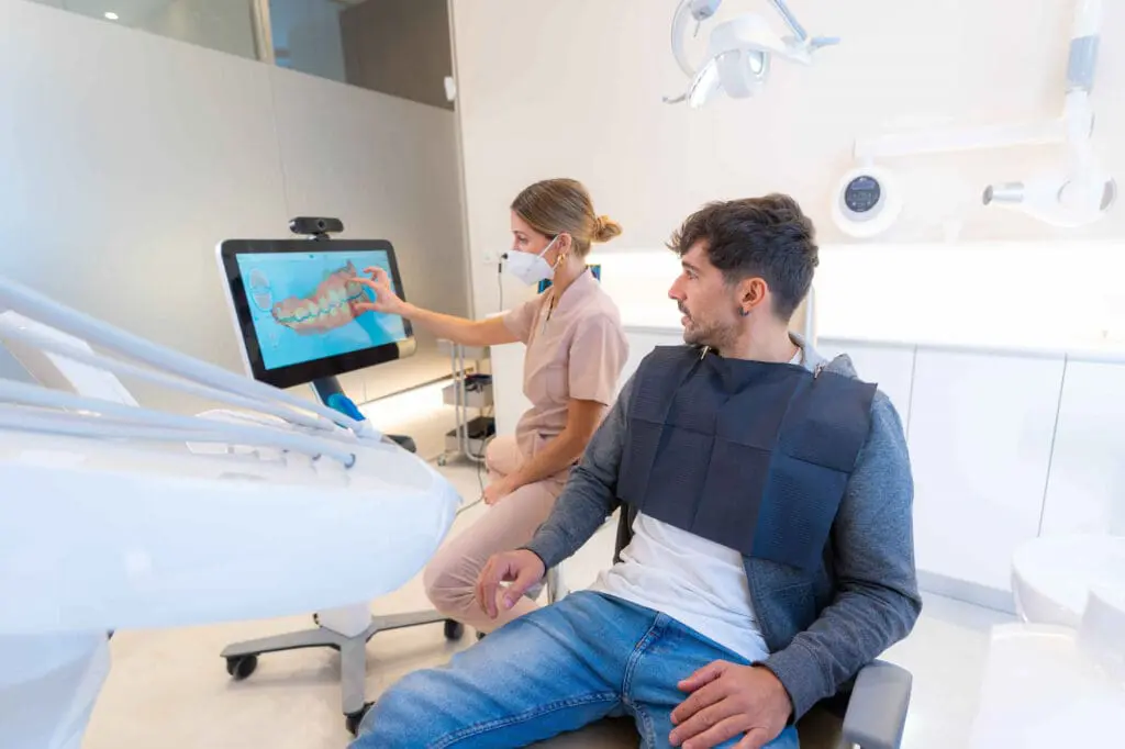 In Austin, TX, at Limestone Hills Orthodontics, a dental professional displays a 3D dental scan to a male patient on a touchscreen.